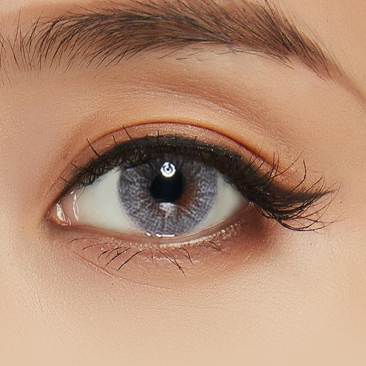 Asian eye wearing Shade Grey contact lenses on top of a dark iris, with natural brown eyeshadow and wispy eyelashes