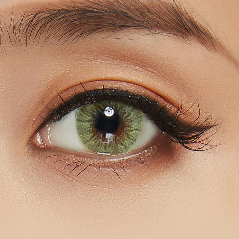 Close-up shot of a model wearing Shade green prescription colored contact lens in one eye that is naturally dark-brown